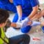 Emergency First Aid at Work online course: paramedics treating a worker in a hi-vis vest on the ground