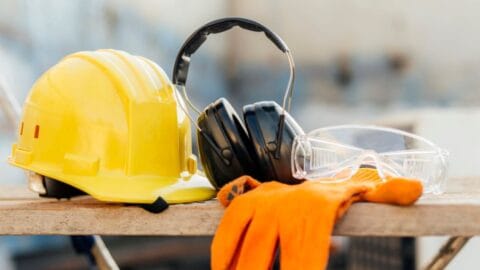 Health and Safety Level 1 online course: yellow hard hat, ear defenders and gloves on a workbench